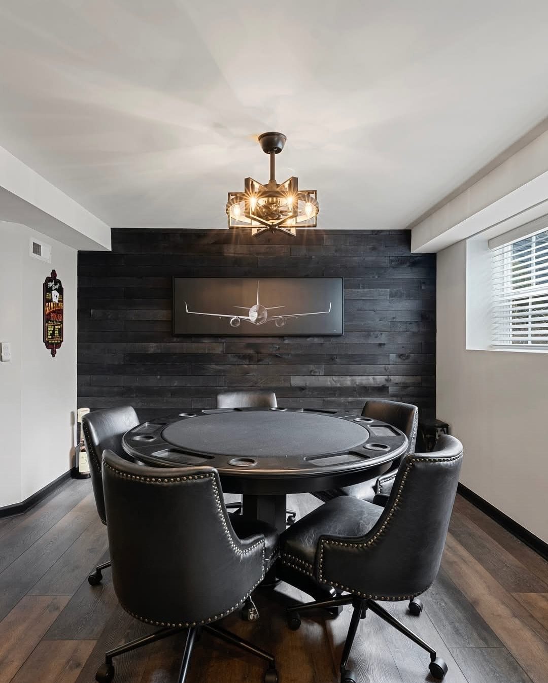 Round black poker table with leather chairs in a modern basement game room