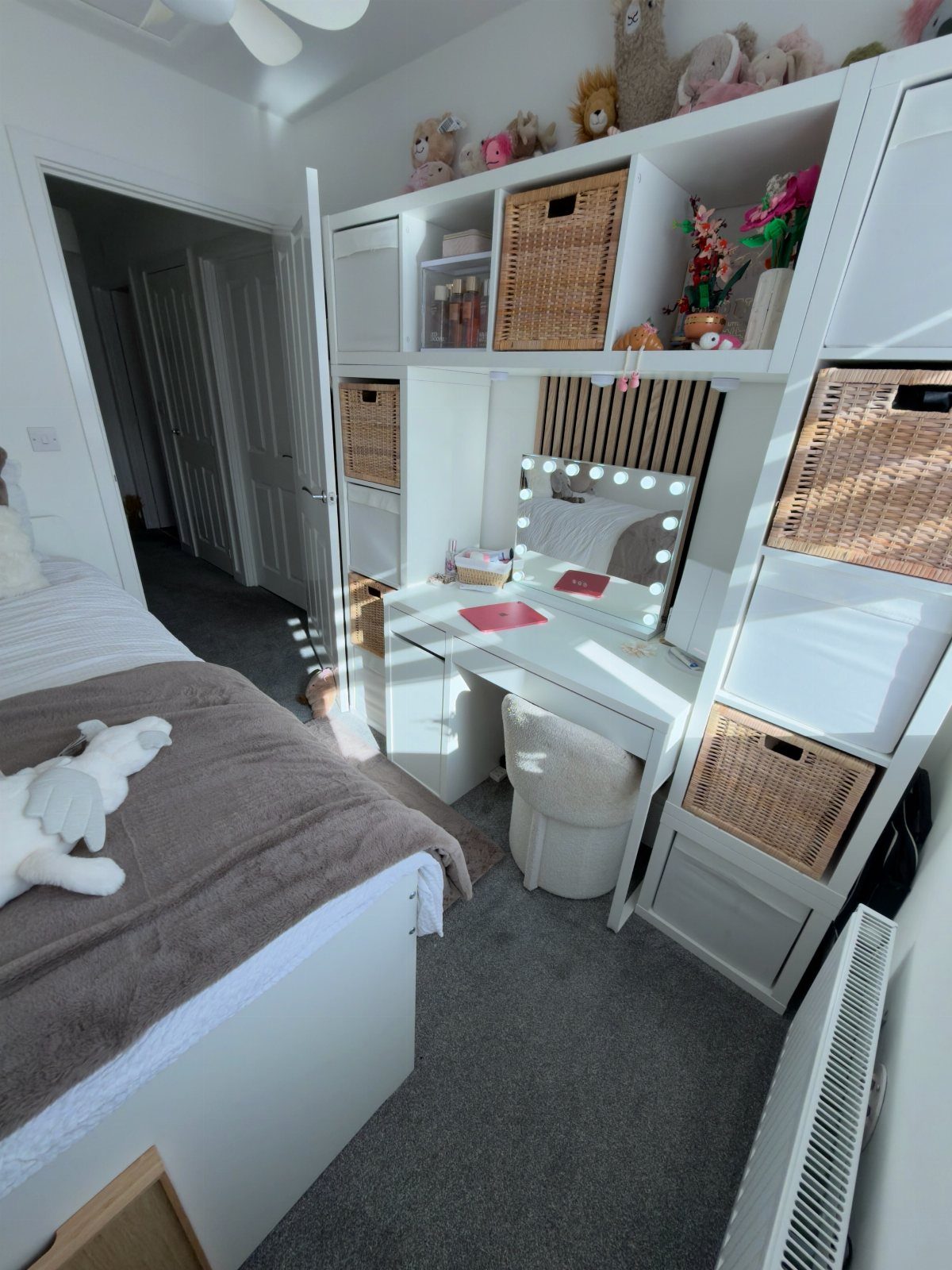 White bed and desk with lighted mirror in a small white bedroom