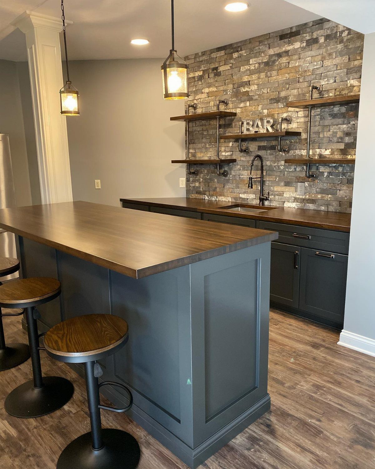 Dark grey cabinets under a wooden countertop in a modern home bar setting.