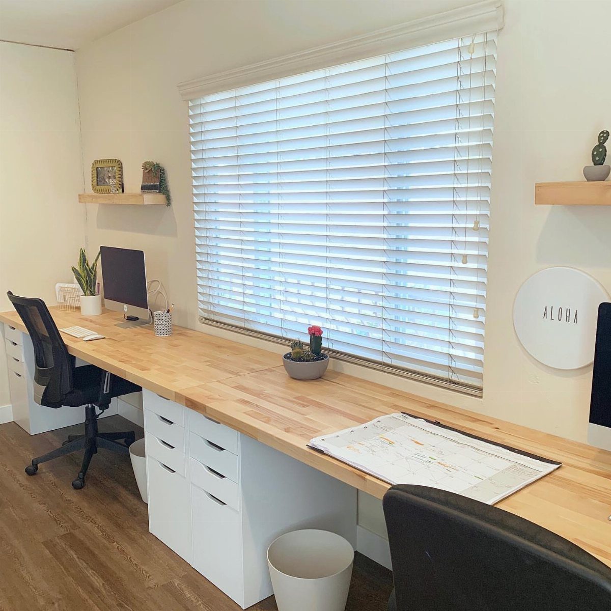 Light wood butcher block desk with white drawers in a bright home office.