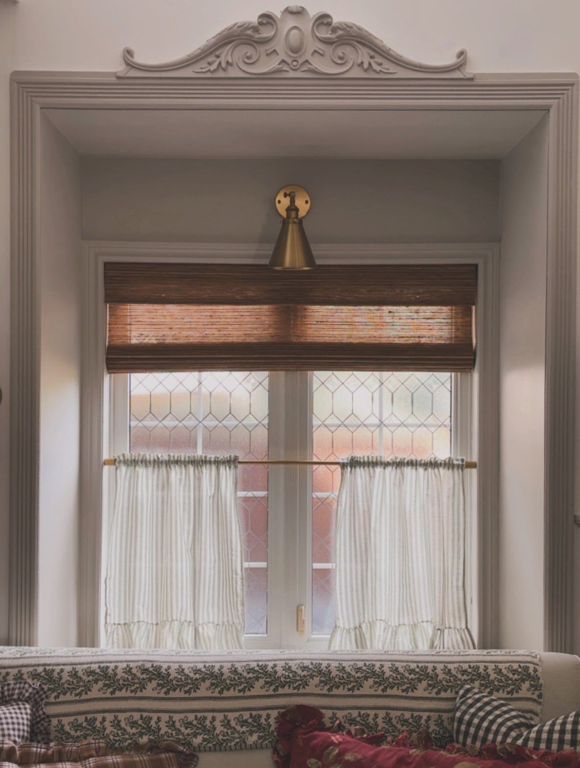 White cafe curtains on the lower half of a leaded glass window.