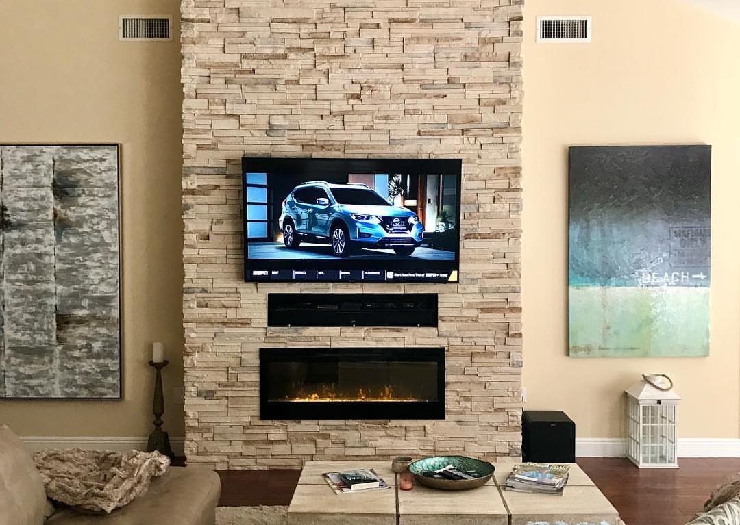 Flat-screen TV mounted above a linear electric fireplace on a stacked stone wall.