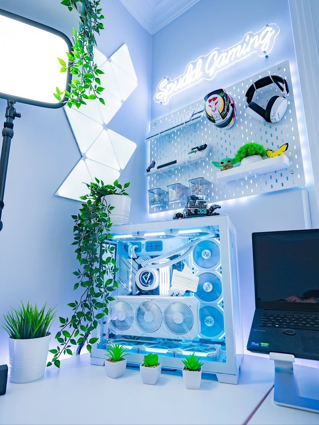 White gaming desk setup with blue LED lighting, PC case, and wall decorations.