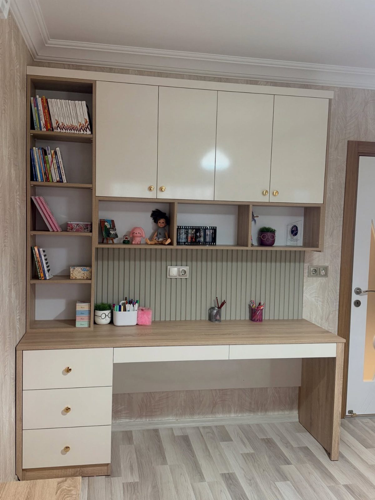Light wood home office desk with integrated shelving and overhead cream cabinets.