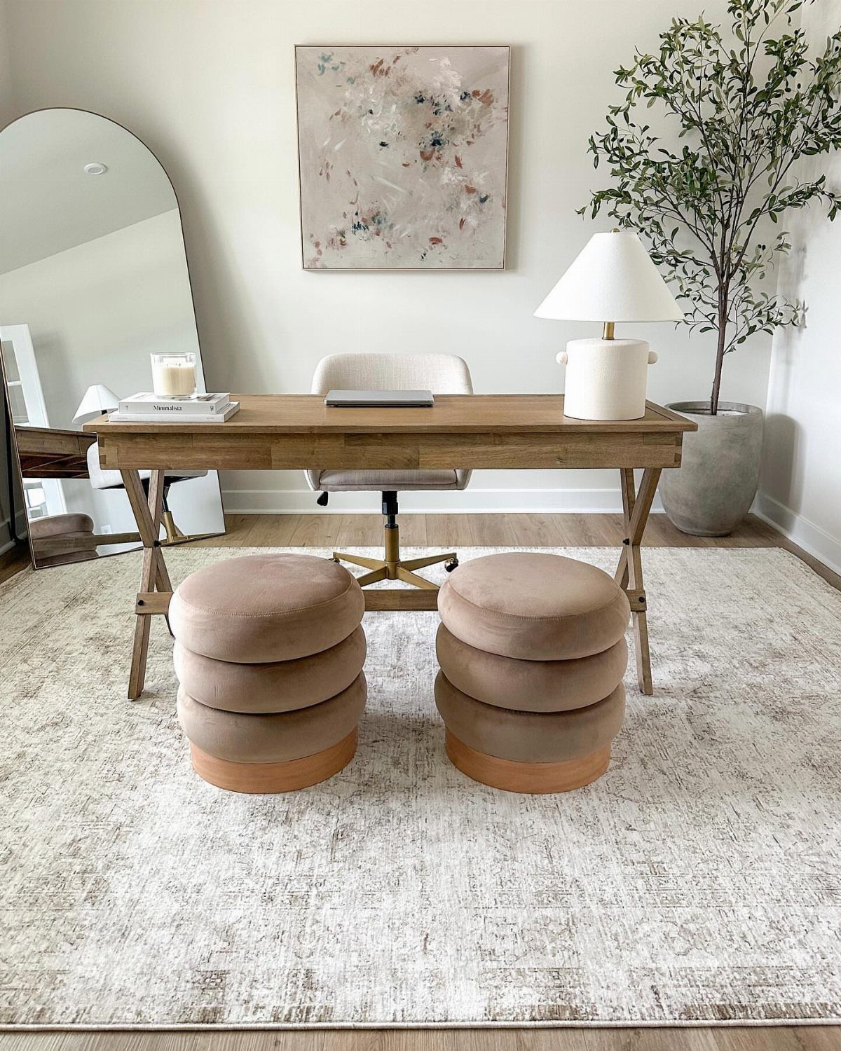 Wooden desk and beige ottomans sitting on a large light-colored patterned area rug.