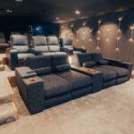 Plush reclining theater seats in a modern home cinema with accent wall lighting.