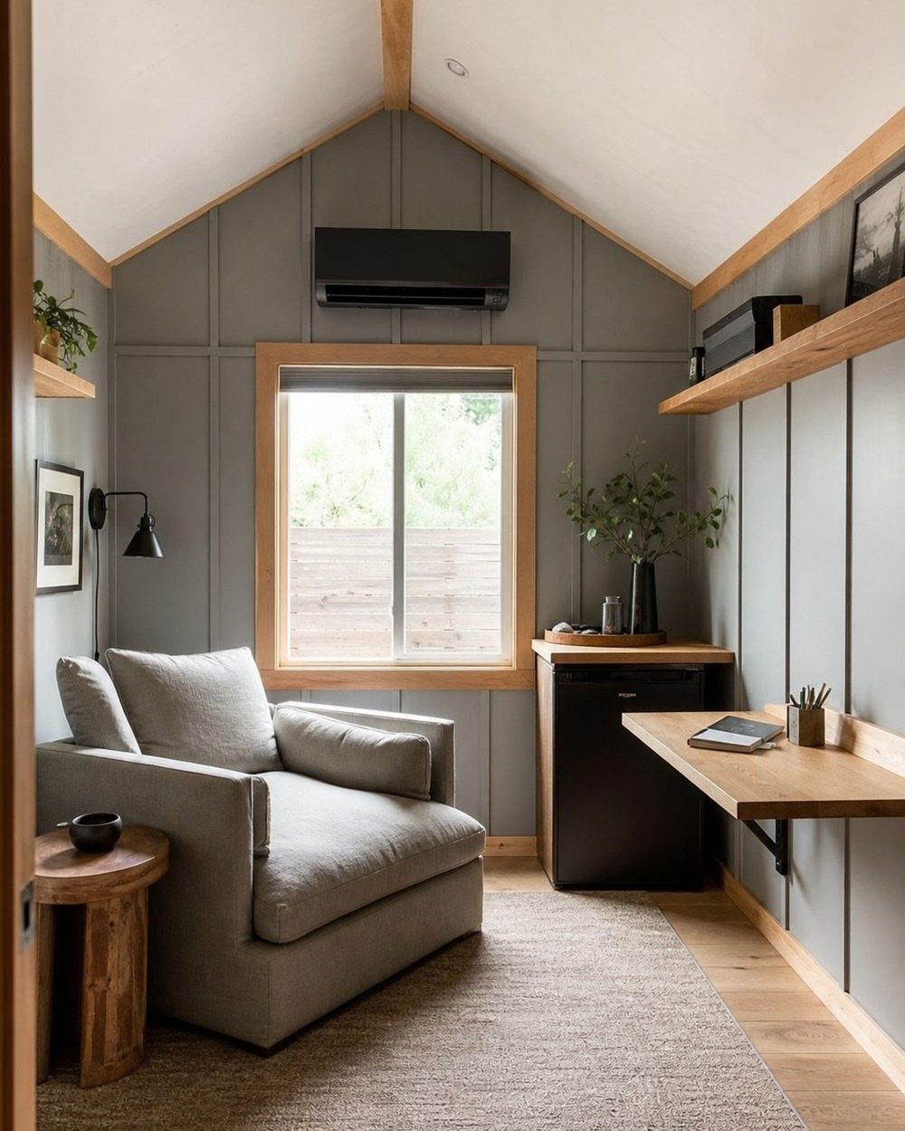 Grey armchair and wooden desk in a modern room with grey paneled walls.