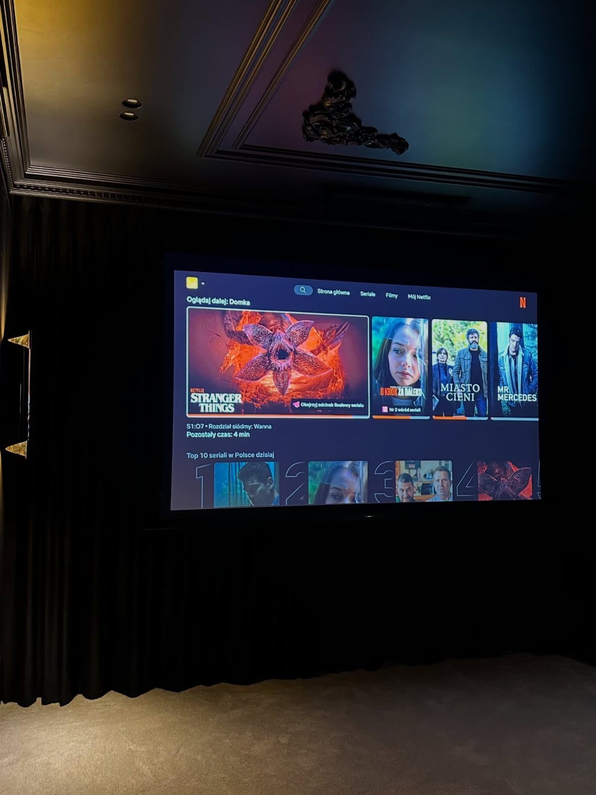 Large projection screen displaying movie options in a dark home cinema room