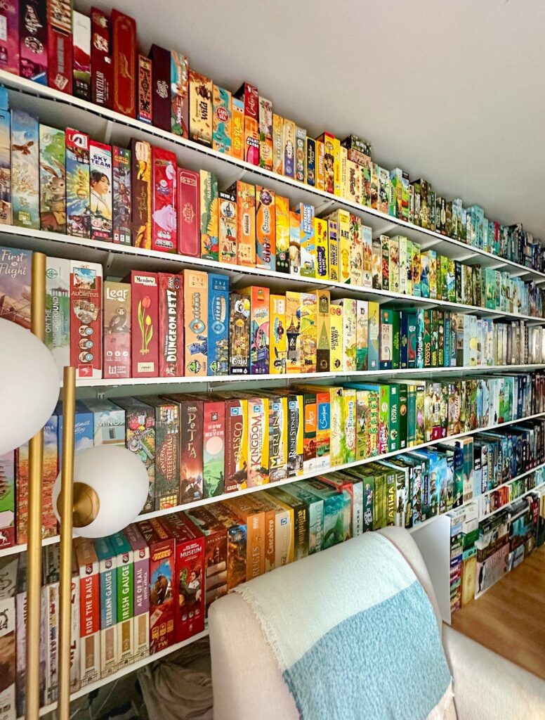 White shelves filled with a large collection of colorful board game boxes.