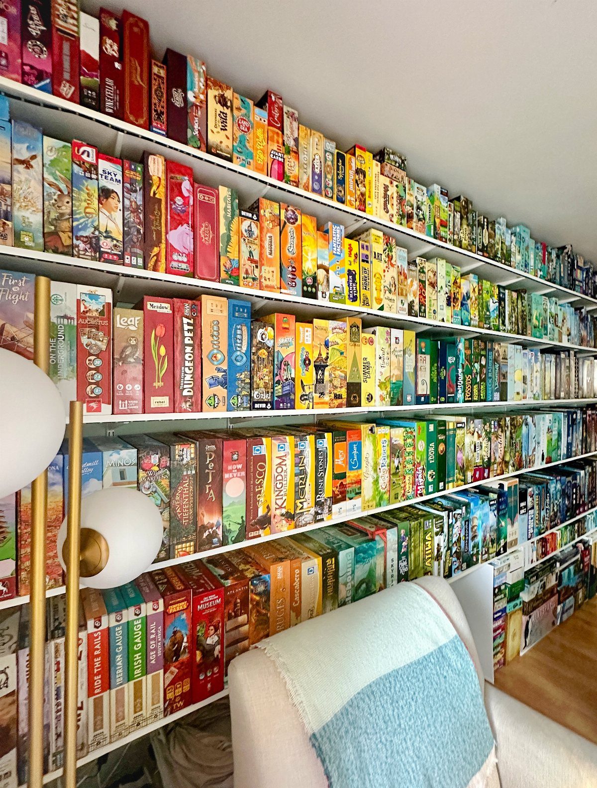 White shelves filled with a large collection of colorful board game boxes.