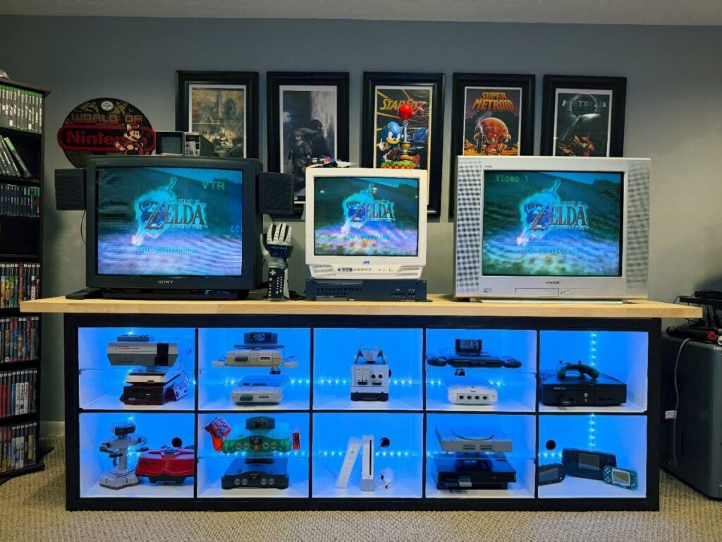 Vintage game consoles displayed in a black shelf with blue LED lighting.