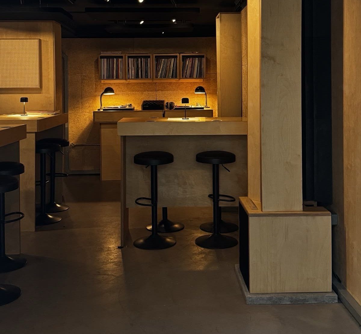 Modern wooden bar counters with black stools and vinyl records in a basement.