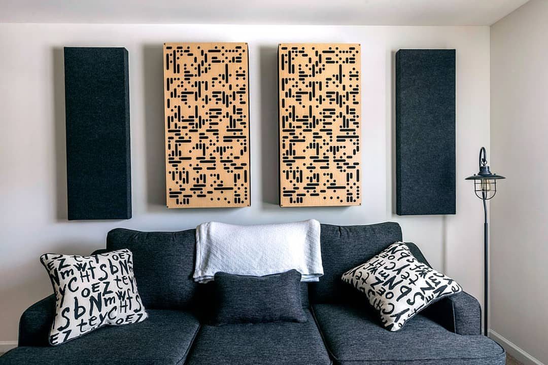 Acoustic panels in black and patterned wood mounted above a grey sofa.