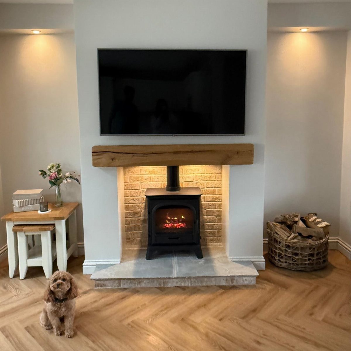 Flat-screen TV mounted above a wooden mantel and black wood-burning stove fireplace.